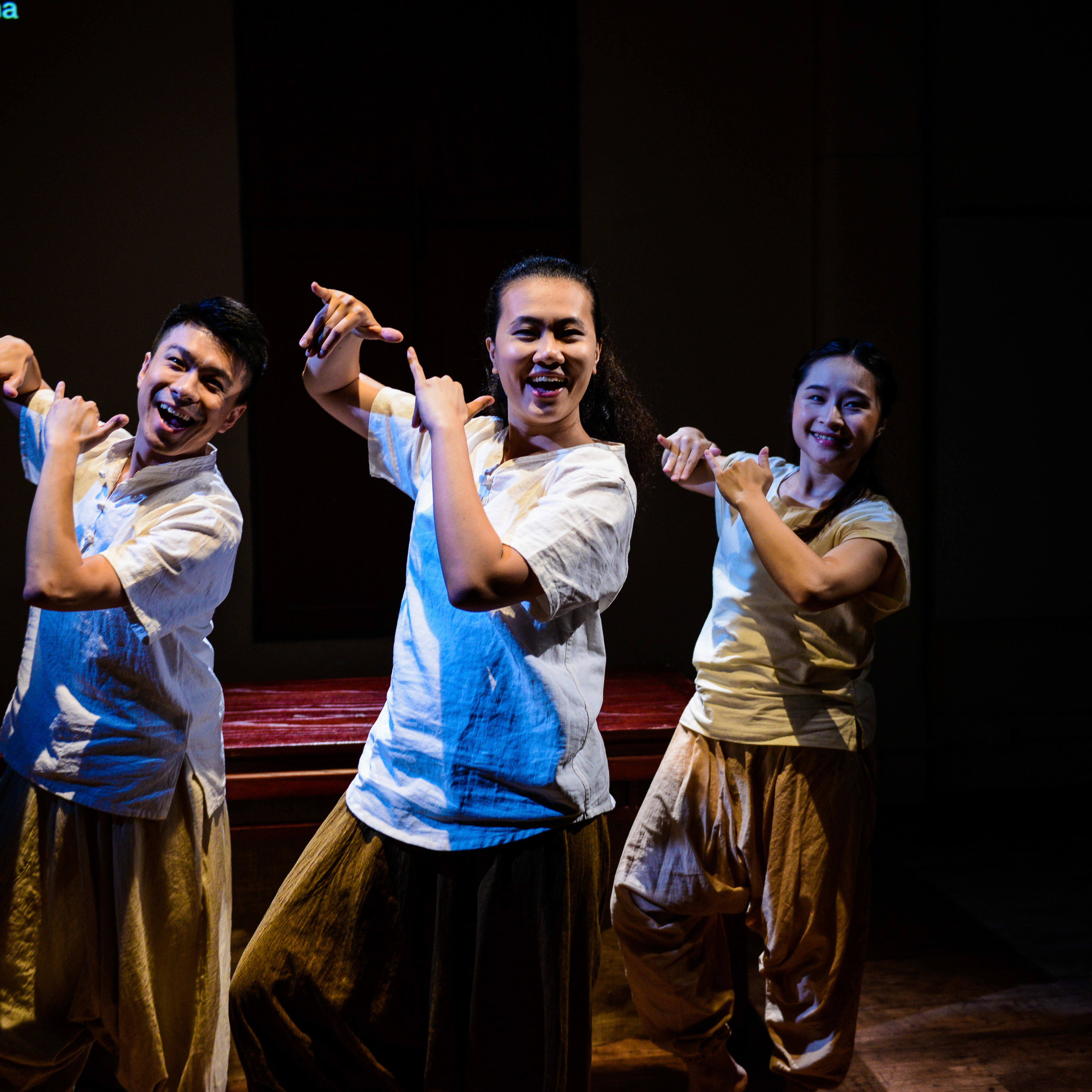 三位演員在天台製作的當代劇場作品《牛奶與蜜糖》中演出編舞片段。他們身穿一致的奶油色上衣與寬鬆長褲，在幽暗的極簡舞台燈光下擺出富感染力的姿態。施標信、李婉晶與隆藹宜共同演繹了劇中充滿象徵意義的一刻。《牛奶與蜜糖》