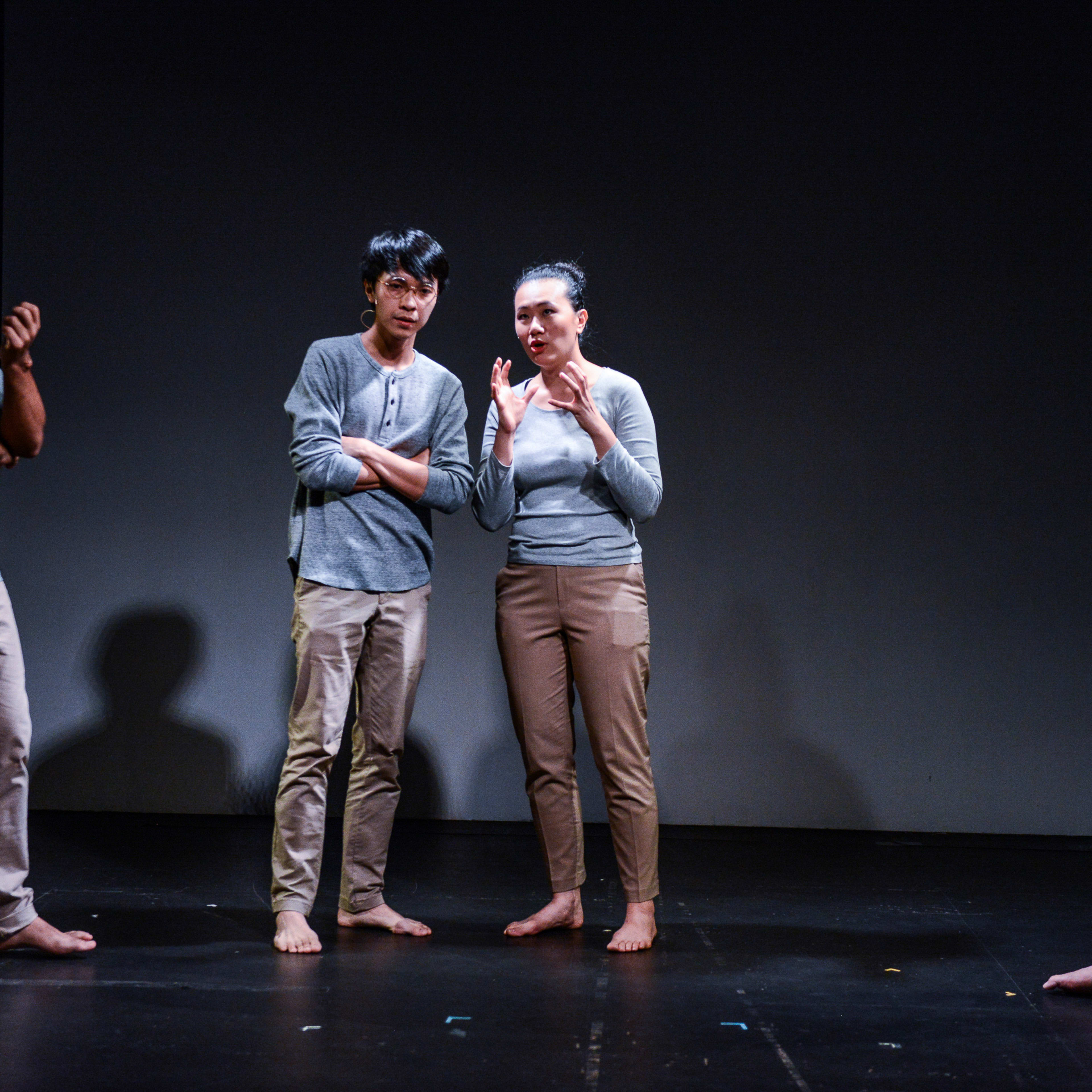 四位演員在天台製作 (Rooftop Productions) 當代劇場作品《山下的證詞》(Testimony) 的舞台上演出，燈光簡潔且充滿張力。從左至右依次為巫加沙、吳景隆、李里莎與李婉晶，他們身著大地色系的休閒服裝，在極簡的舞台佈景中呈現出深刻的情緒張力，展現香港當代劇場獨特的敘事風格。「《山下的證詞》」