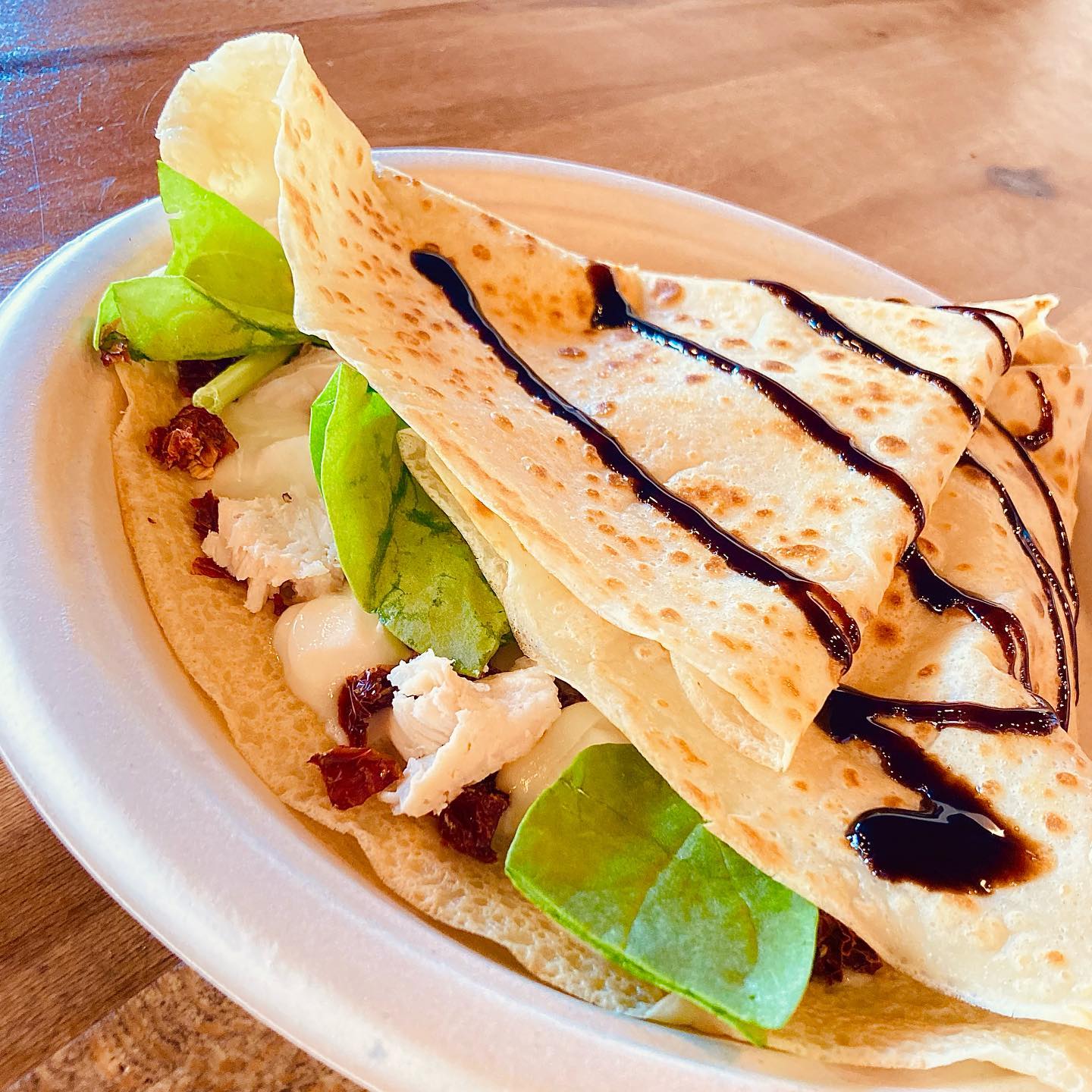 A Caprese crepe garnished with balsamic glaze.