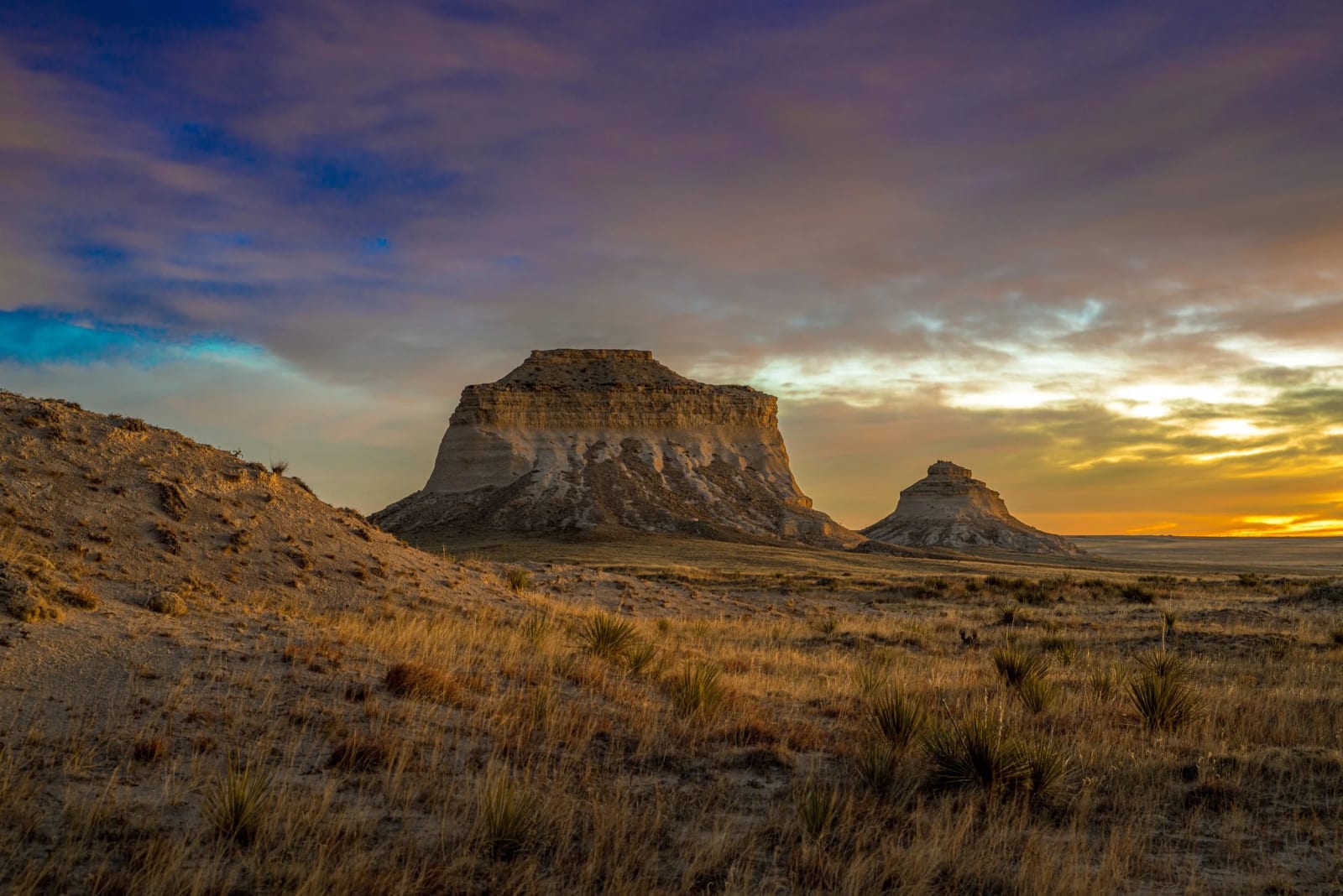 The Prairie Does Drama Quietly — Pawnee National Grassland, Colorado. The pair of Pawnee Buttes trading light with a moody dawn sky over the Colorado…
