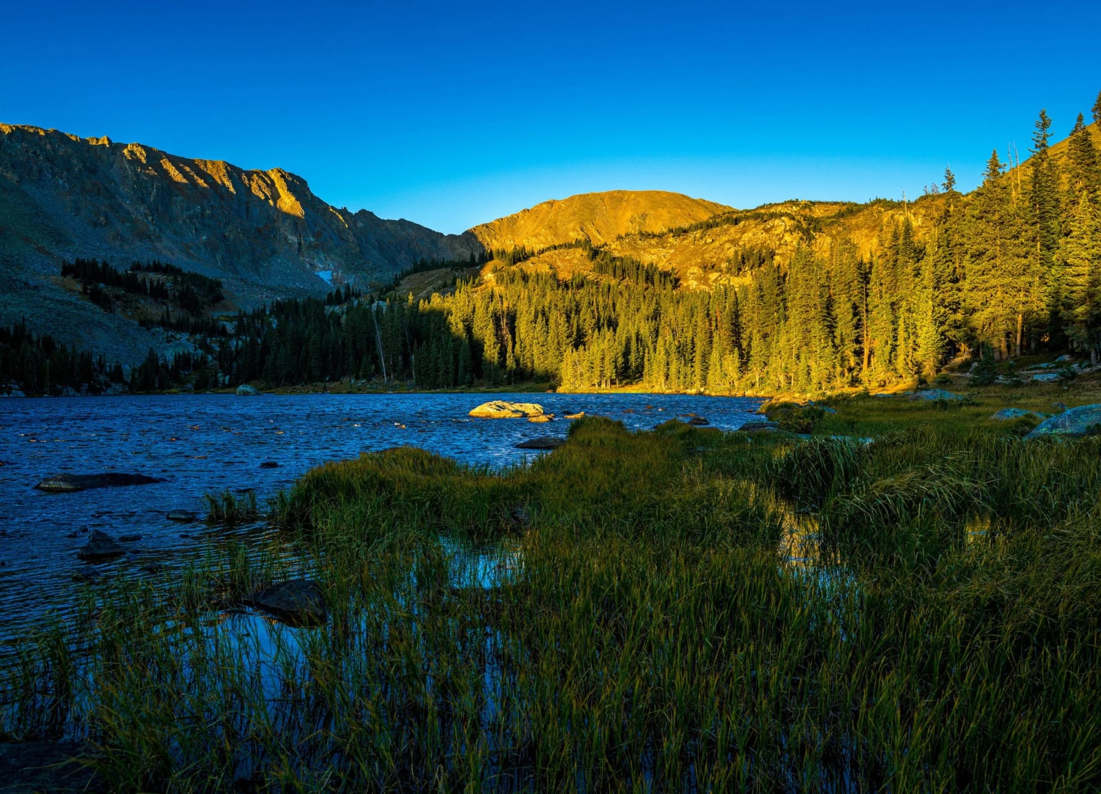 First Sun Up the Ridge — Indian Peaks Wilderness, Colorado. First light working down the ridge above an alpine lake while the water and the near shore are…