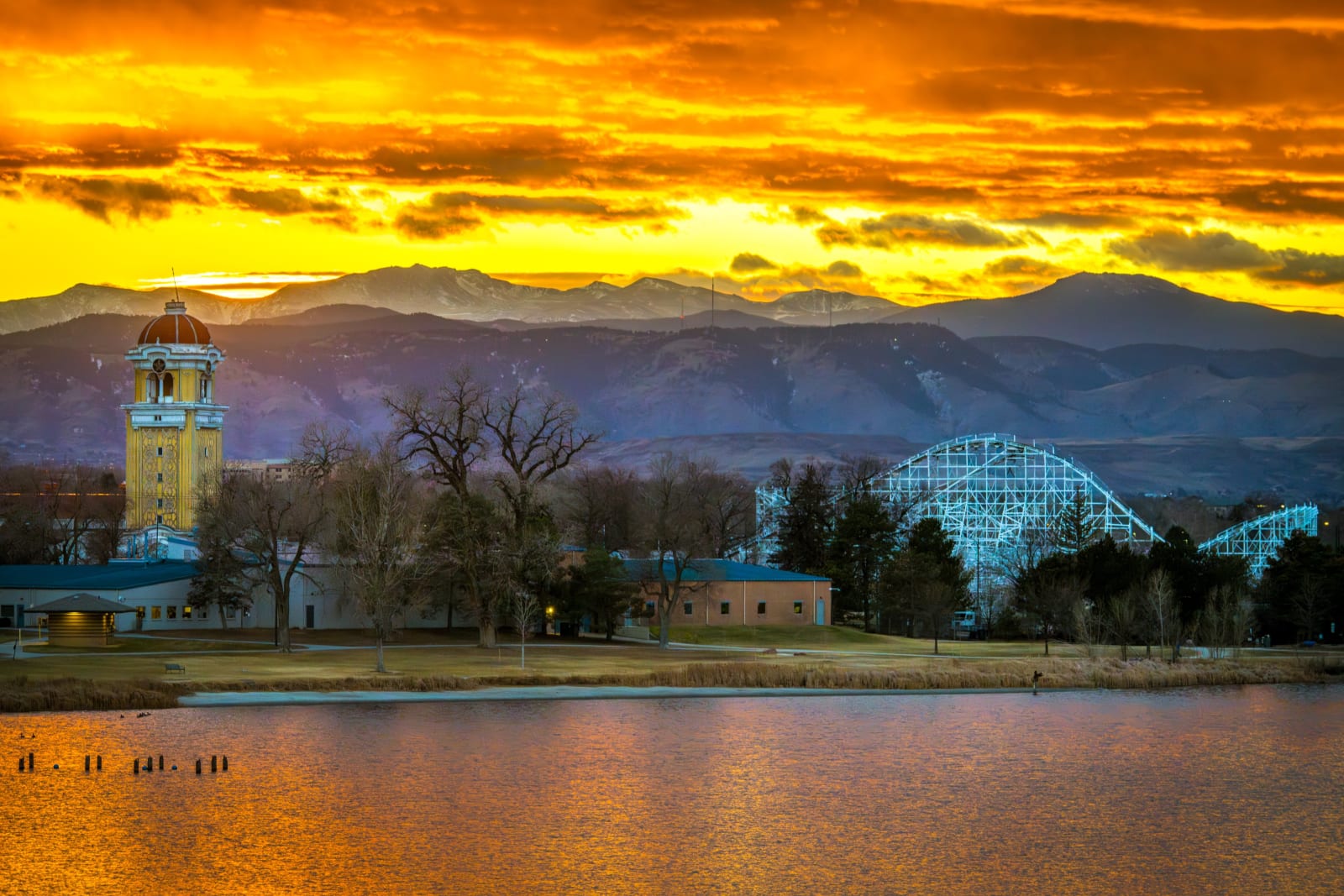 Sunset Over the Midway — Berkeley Lake Park, Denver. Sunset burning orange over Berkeley Lake in Denver, with the Lakeside Amusement Park tower and the old…