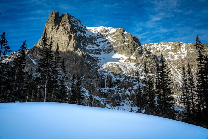 It Just Stands There and Dares You — Rocky Mountain National Park, Colorado. Notchtop Mountain shouldering into a hard blue Colorado sky above a snowfield…