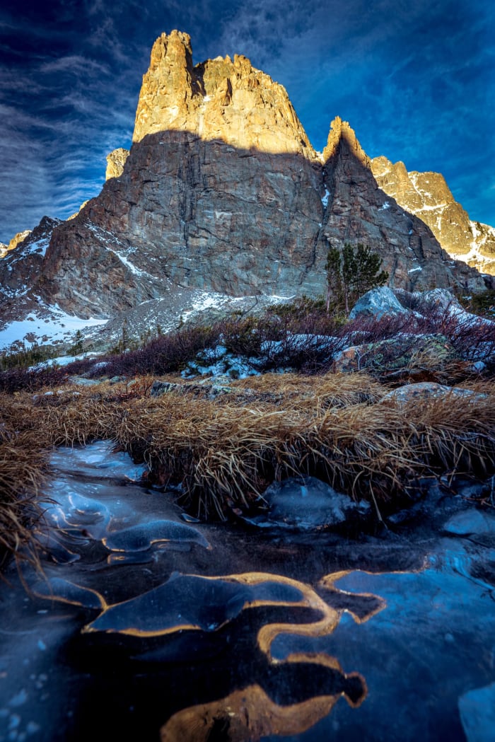 Vertical From Top to Bottom — Rocky Mountain National Park, Colorado. Notchtop Mountain lit up while the tarn below stays in frozen shadow, gold grass…