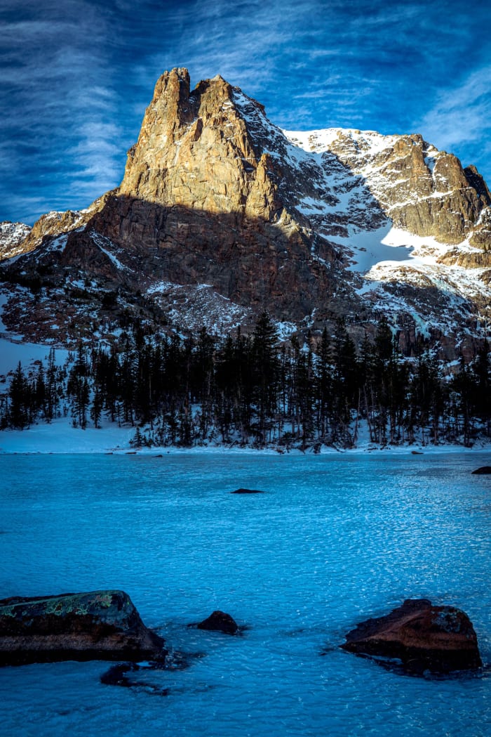 Notchtop Over Blue Ice — Rocky Mountain National Park, Colorado. Notchtop Mountain catching morning sun above a lake locked in blue ice in Rocky Mountain…