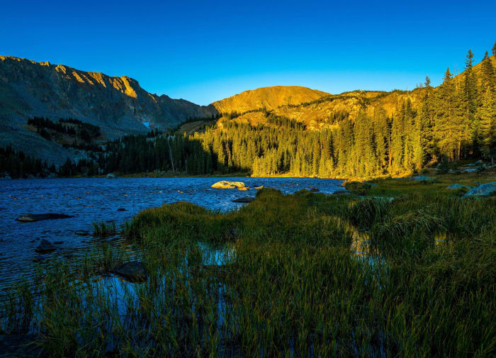 First Sun Up the Ridge — Indian Peaks Wilderness, Colorado. First light working down the ridge above an alpine lake while the water and the near shore are…