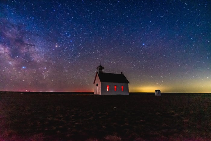 Little Church on the Prairie — Abbott, Colorado. The Milky Way rising over a lone white church on the plains near Abbott, Colorado, with red light glowing…
