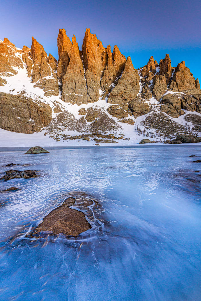 Spires Over a Frozen Pond — Sky Pond, Rocky Mountain National Park, Colorado. Morning light on the Sharkstooth and the jagged spires above Sky Pond in Rocky…