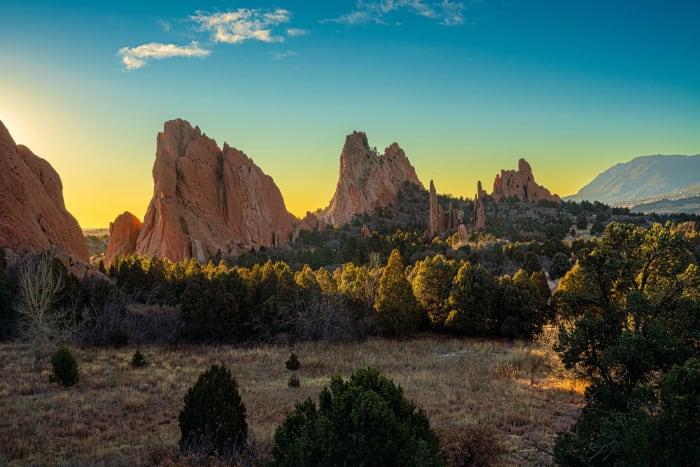 Pikes Peak Keeps an Eye on Things — Garden of the Gods, Colorado Springs, Colorado. The sun cresting behind the spires at Garden of the Gods with Pikes Peak…