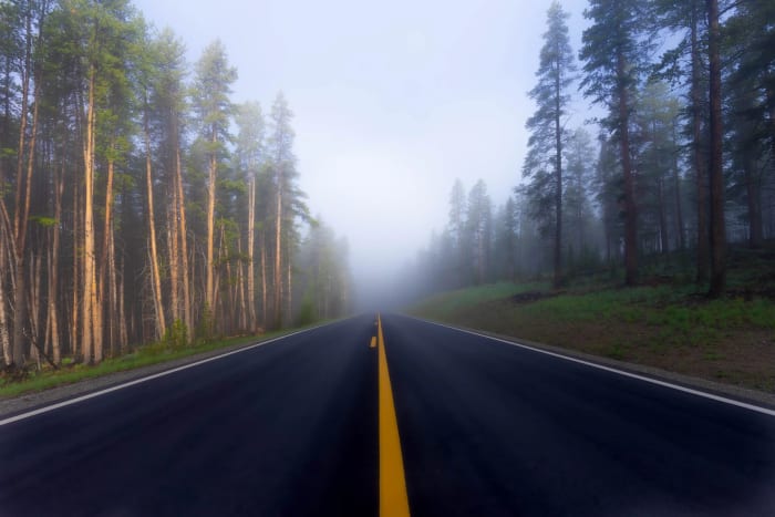 Standing on the Yellow Line — Cottonwood Pass, Colorado. Dead center on the centerline with a wall of fog swallowing the road ahead and tall pines lining…