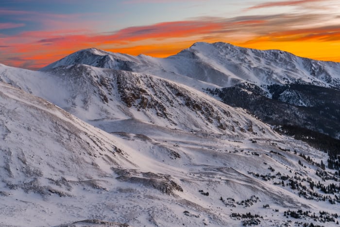 Snowy Sunrise at Loveland Pass — Loveland Pass, Colorado. Orange dawn spreading over the snowfields and rock ribs of Loveland Pass, Colorado, with the…