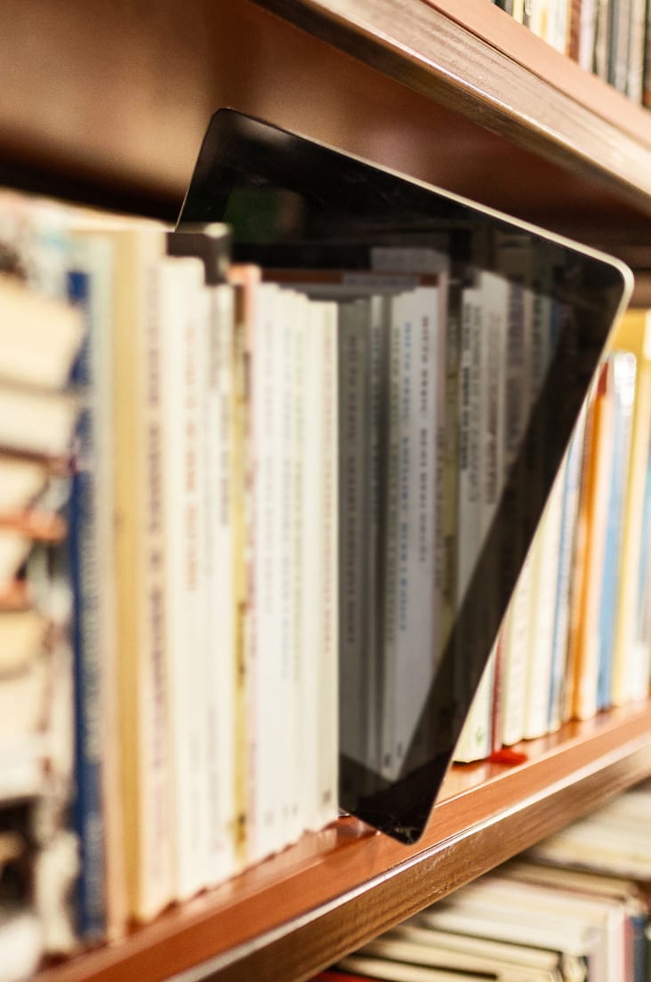 Bookshelf with many books and single e-book reader