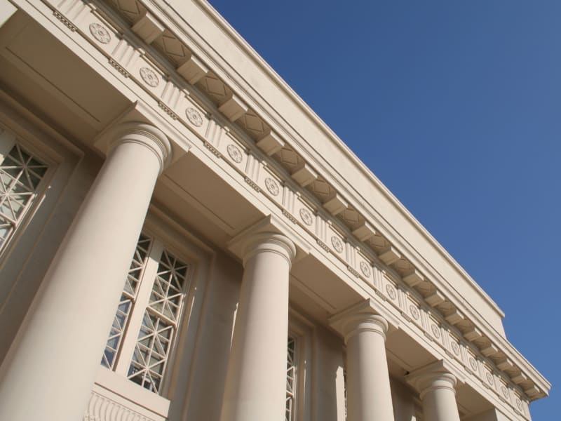The edge of a building with a portico against the sky