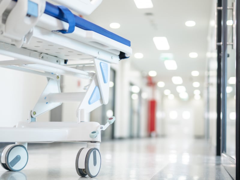 A hospital bed in a white corridor