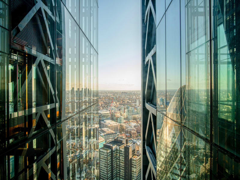 A panoramic view of the city visible between two glass skyscrapers