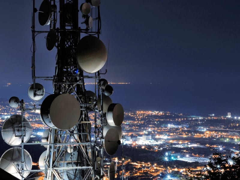 A mast with satellites against the backdrop of the city at night