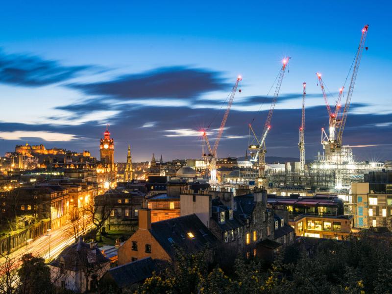 A series of cranes at a major construction site in central Edinburgh, seen on the skyline alongside the city's traditional landmarks