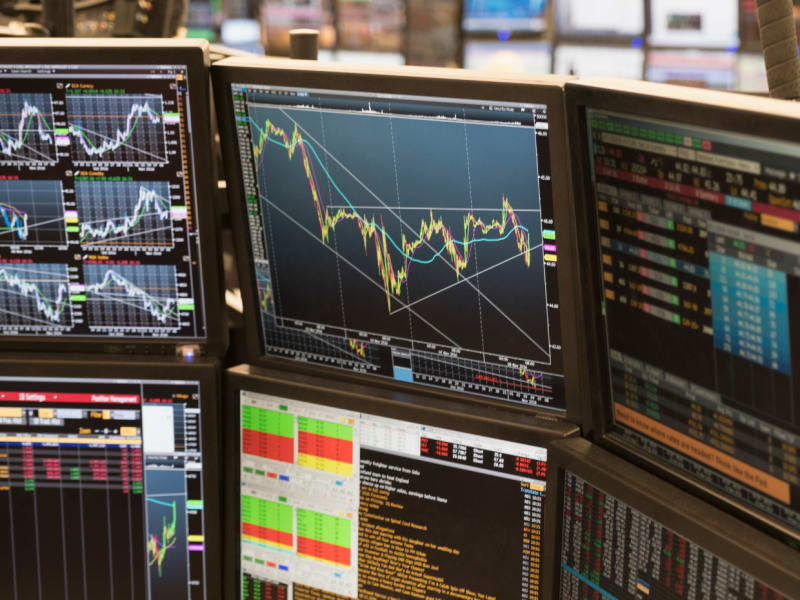 A row of monitors displaying stock market charts and statistics