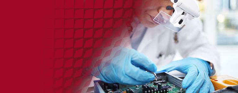 A technician wearing blue gloves, inspecting a circuit board for overheating issues.