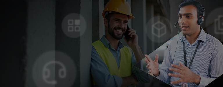 Image of two men. First man on the phone wearing hard hat and high vis vest, second man in blue shirt wearing a customer service headset.