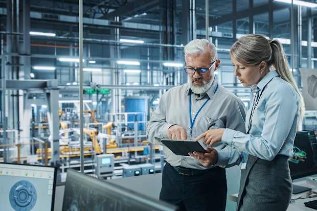 Professionals looking at iPad with factory in background