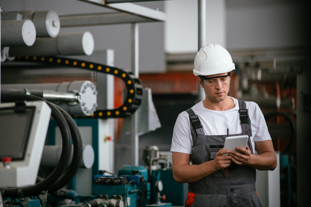 Man using tablet in a factory to monitor machines