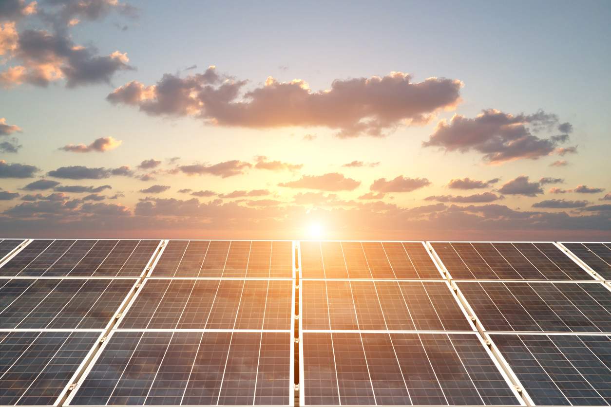 Shot of solar panels generating power from the sunset overhead.