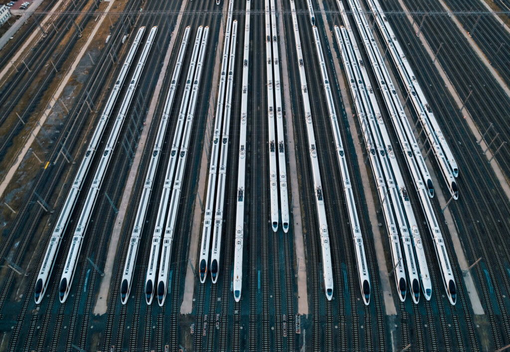 A row of white, high speed trains docked in a railyard