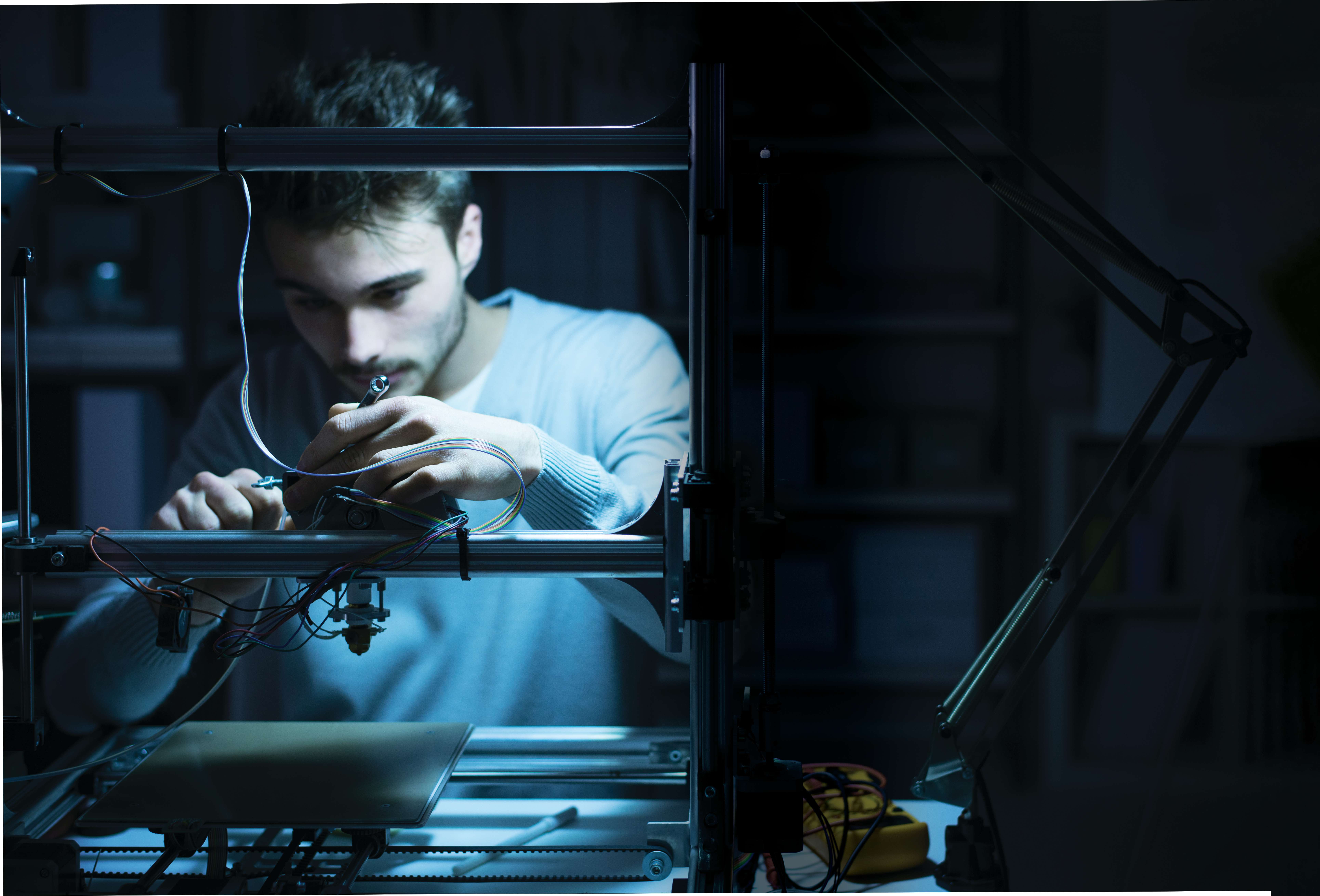 An engineer upgrading a system with modern sensors, in a darkly lit workshop.
