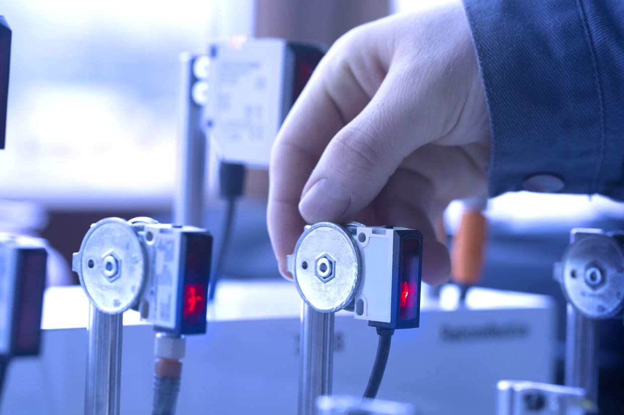 An engineer calibrating a predictive sensor in a dimly lit factory.