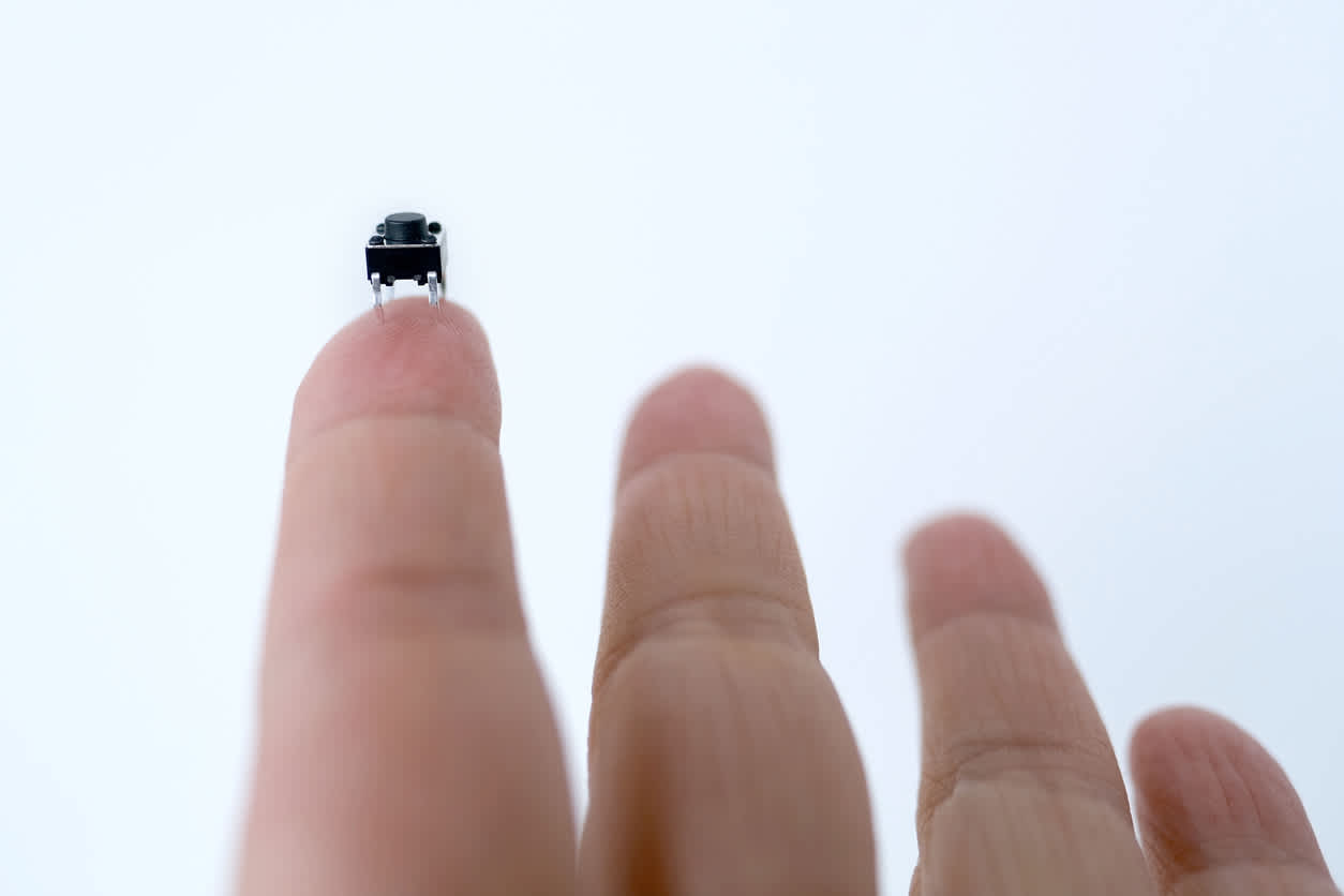 Dito che regge un minuscolo interruttore a levetta miniaturizzato