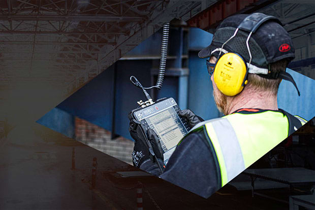 Person wearing ear defenders while viewing results of checks on vibration tester