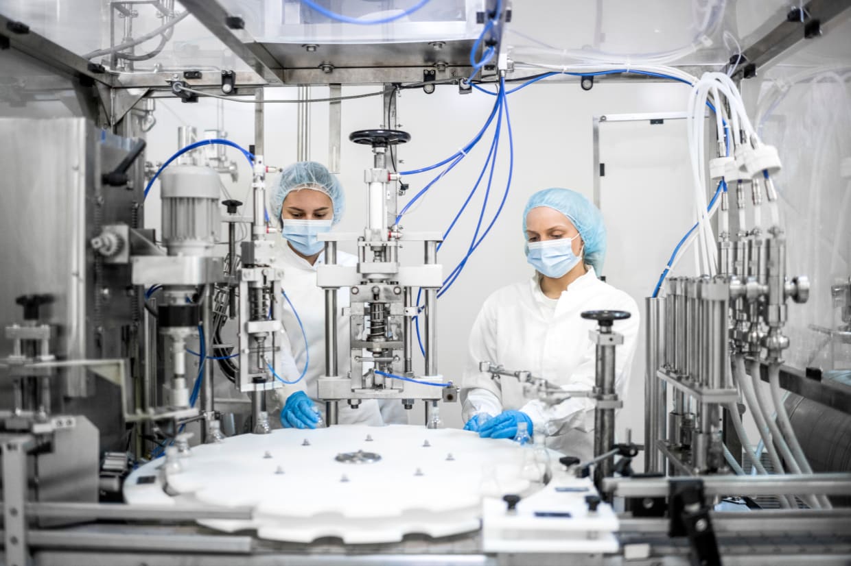 Dos trabajadoras con EPI en una planta de producción farmacéutica