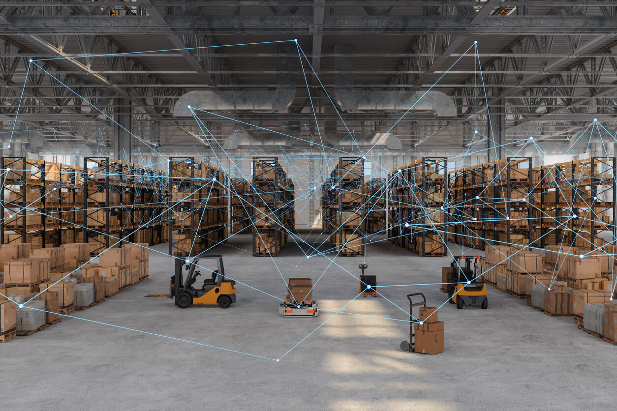A warehouse filled with boxes, pallets and forklifts with blue digital lines connecting one to one another, to represent AI solutions for inventory management.