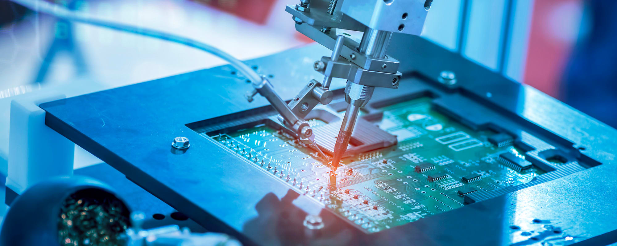 High-precision robotic tool performing additive microfabrication on a printed circuit board, depositing material onto electronic components in an automated manufacturing process.