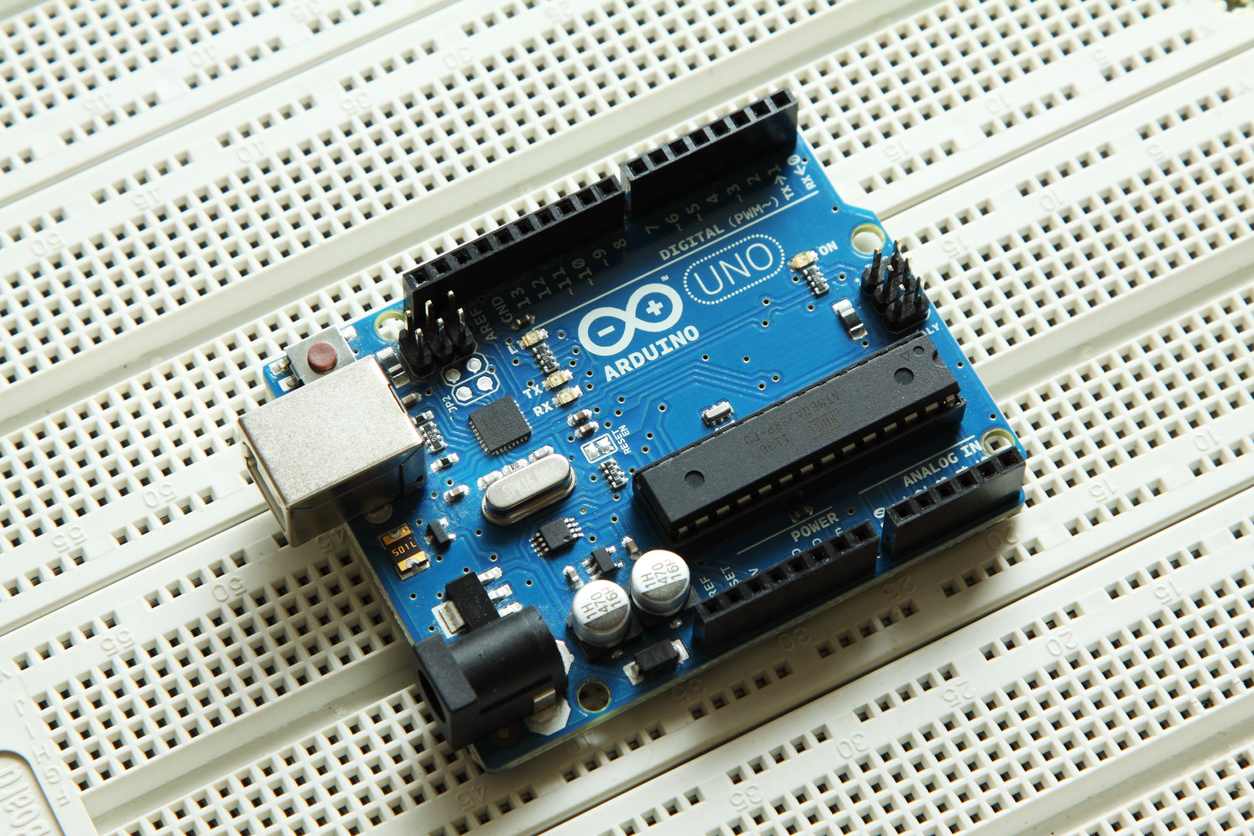 A top down shot of an blue Arduino printed circuit board (PCB) against a white background