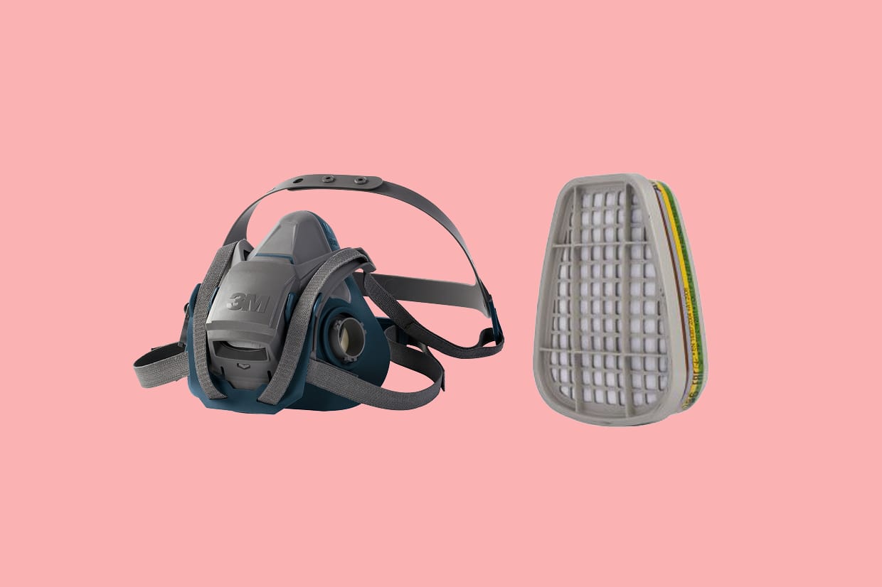A 3M respirator mask next to a filter on a light red background