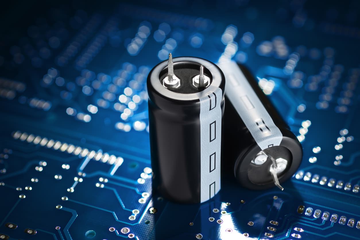 A close up of capacitors placed on top of a blue circuit board.