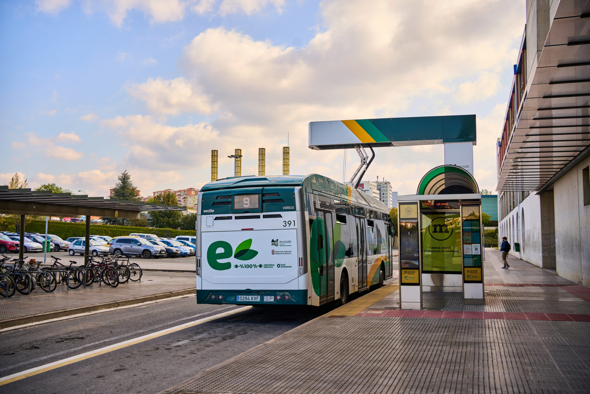 An electric bus stopped at a bus station, waiting for passengers to board.