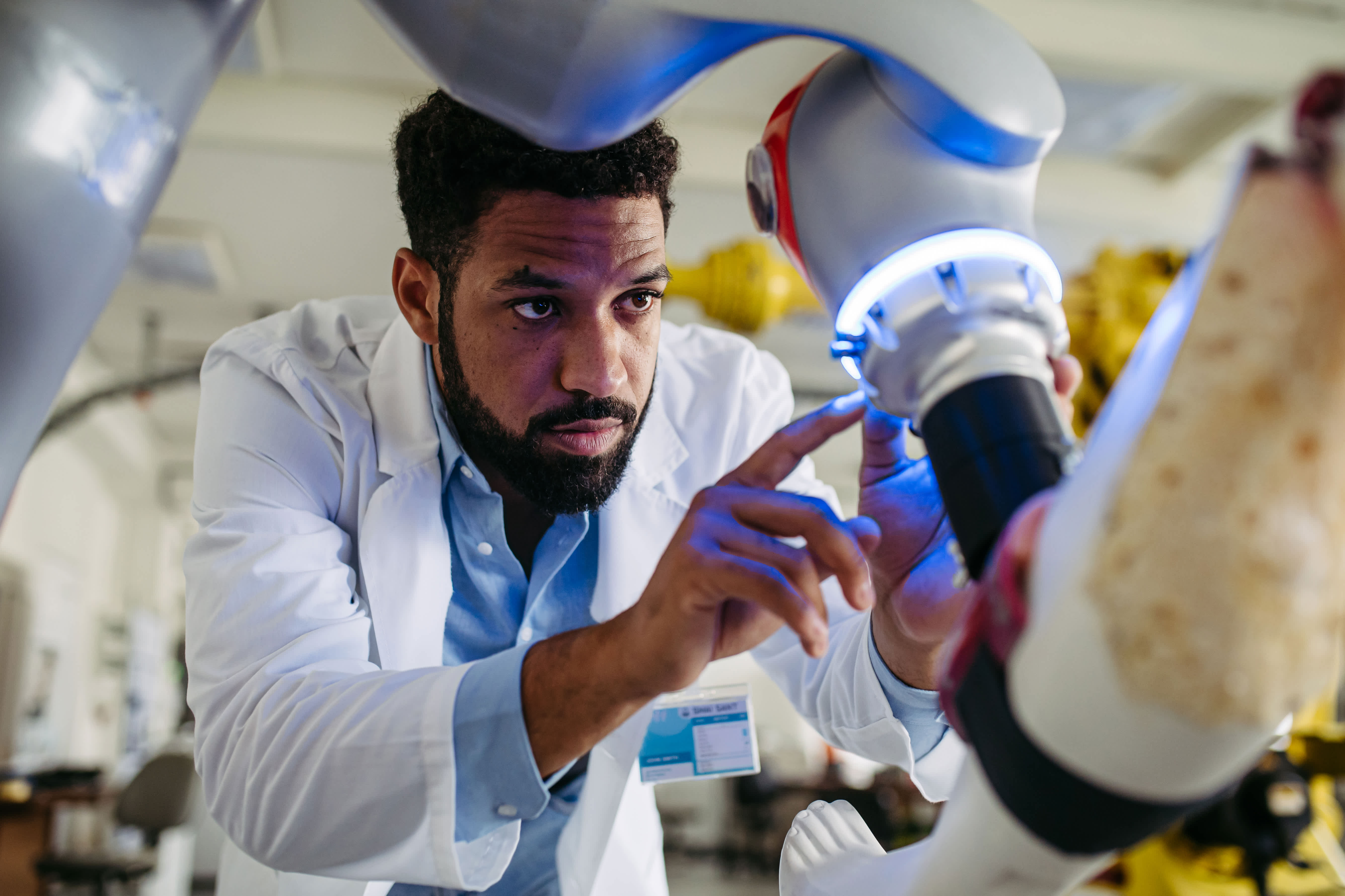 Engineer inspecting and adjusting a surgical robot in a laboratory setting.