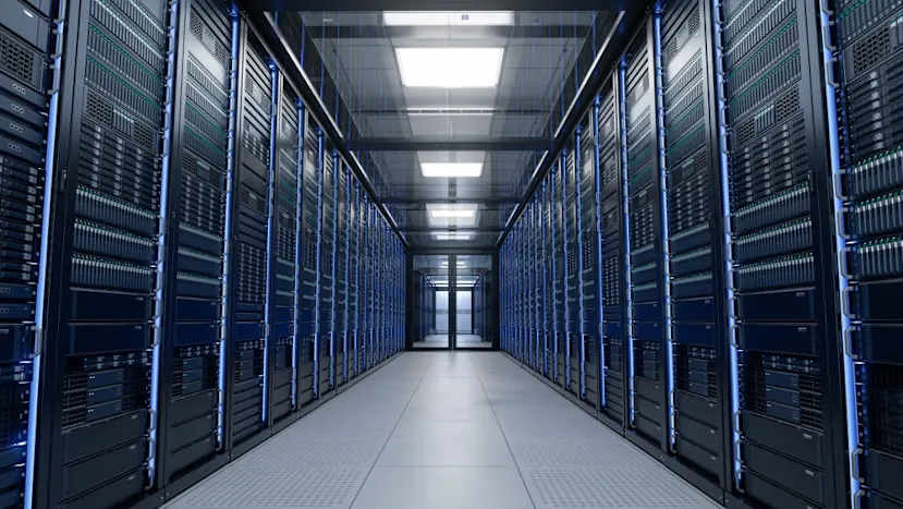 A shot inside of a data centre, looking down a long corridor with servers either side switched on and emitting a blue light