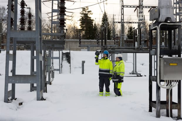 Två personer i varselkläder stående i en kraftstation.