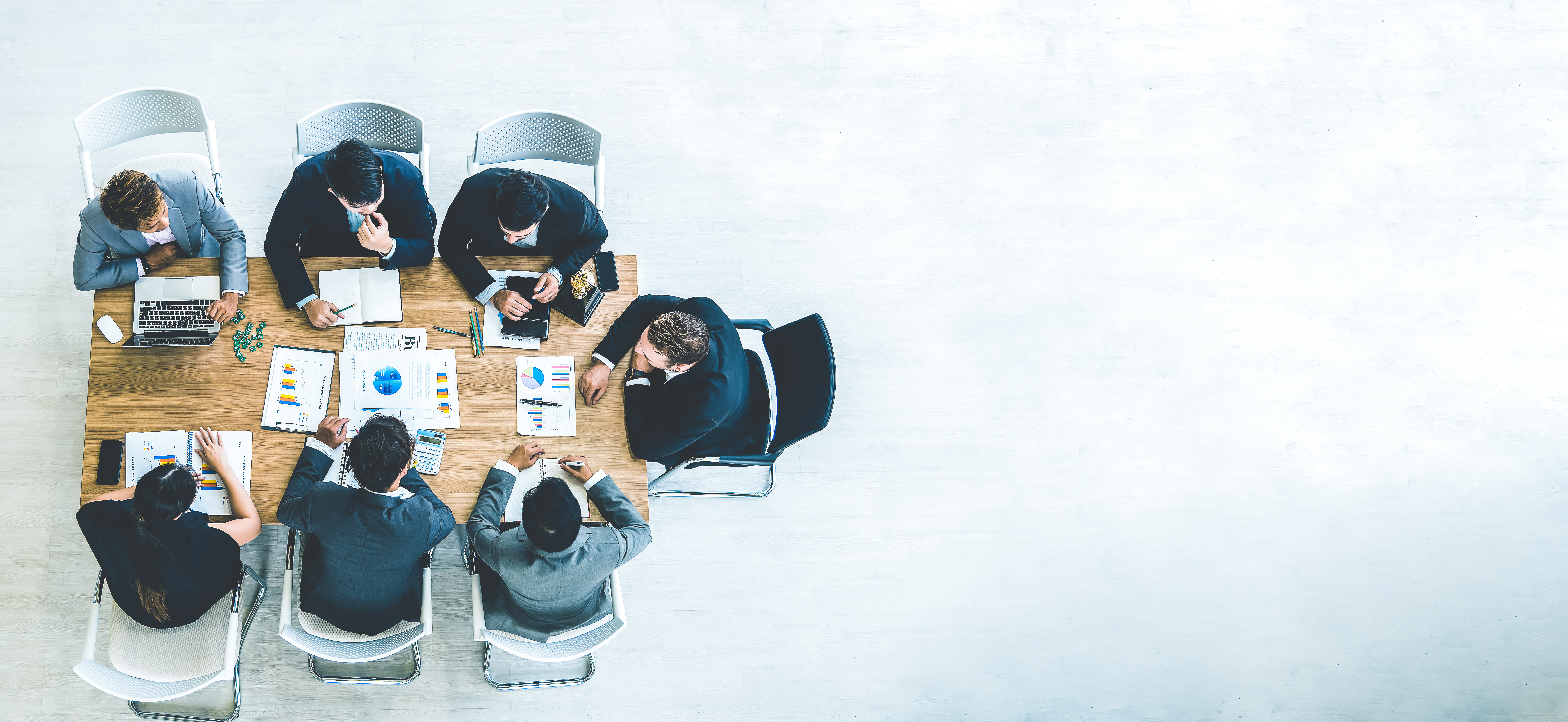 People in suits sat around a table discussing ESG management, looking at laptops and charts.