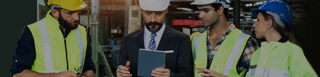 One female and three male engineers standing in a factory having a discussion