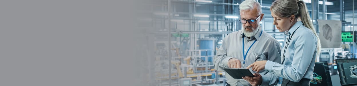 Two people looking at the screen of a tablet in a factory environment