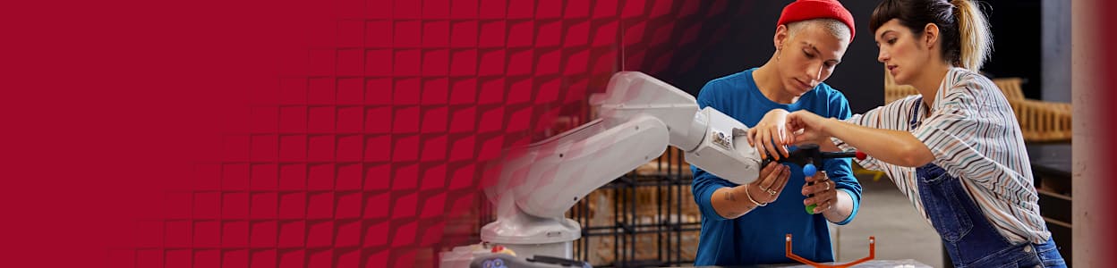 Two engineers working to adjust a robotic arm in a modern workshop.