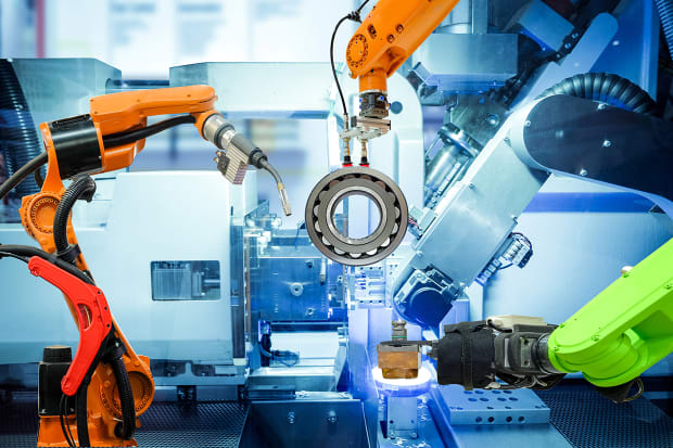 Robotarmar håller metalldetalj i automatiserad fabrik