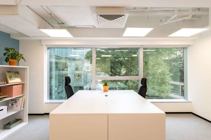 Bright coworking space with large window views, modern furniture, and storage on Queen's Road East.