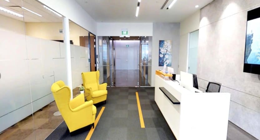 Bright coworking space with modern reception, comfy yellow chairs, and glass accents.