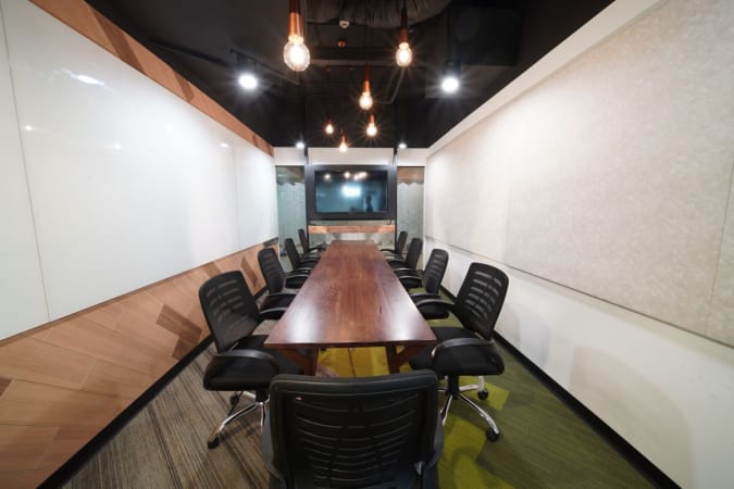 Modern conference room with seating for ten, equipped with a large screen and stylish lighting.